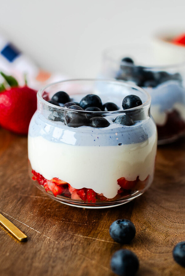 Red, white, and blue cottage cheese parfait layered with fresh strawberries, whipped vanilla cottage cheese, blue cottage cheese, and blueberries in a glass jar.
