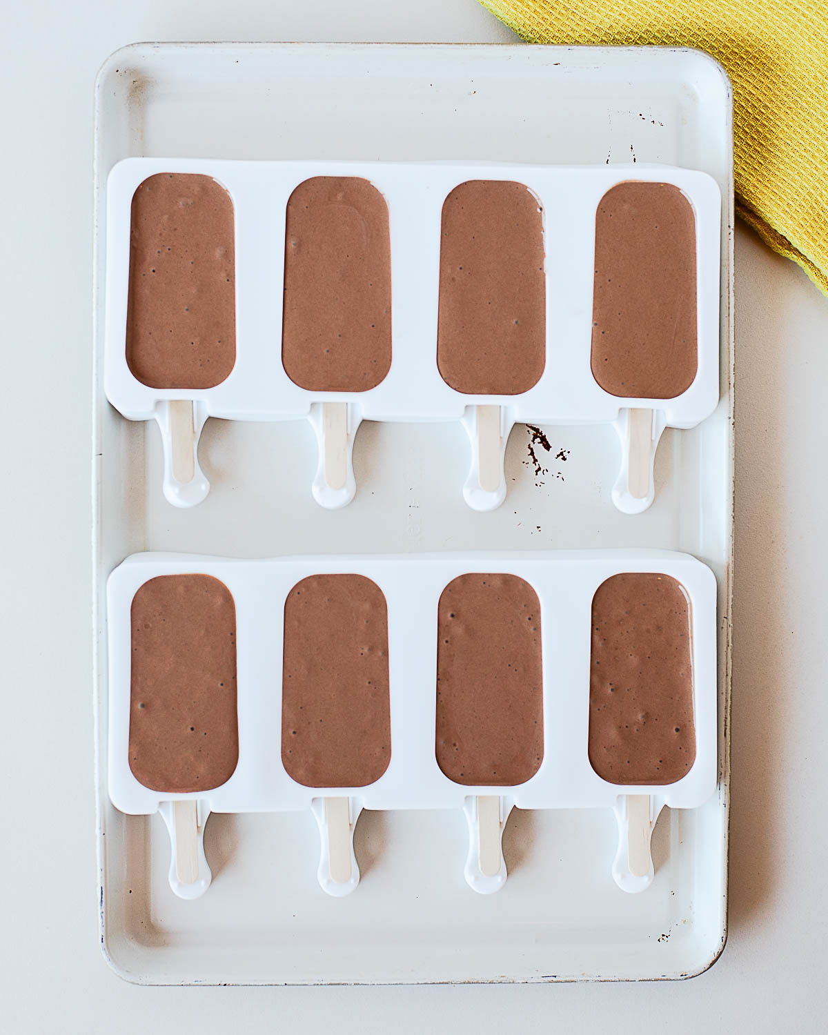 Chocolate protein popsicle mixture blended smooth and poured into white silicone popsicle molds, ready to freeze for an easy high-protein frozen treat.