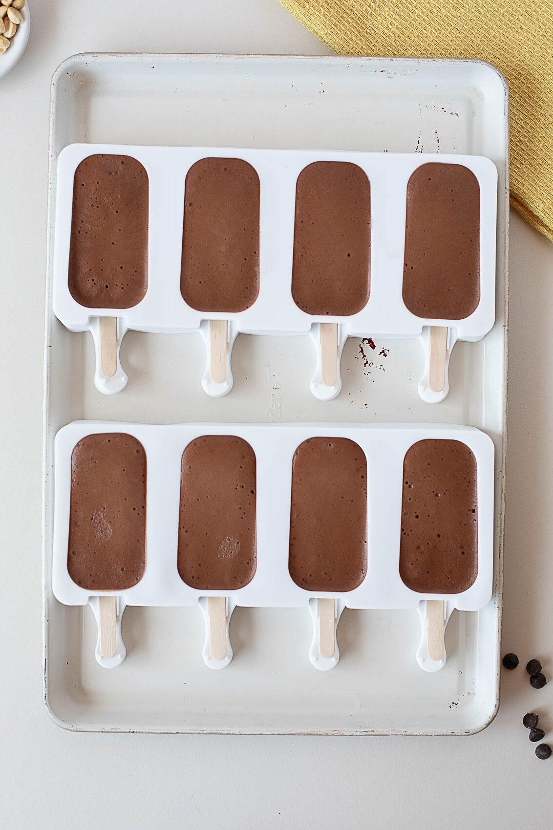 Homemade chocolate protein popsicles in silicone molds before freezing, made with cottage cheese, chocolate protein powder, peanut butter, cocoa powder, and almond milk.