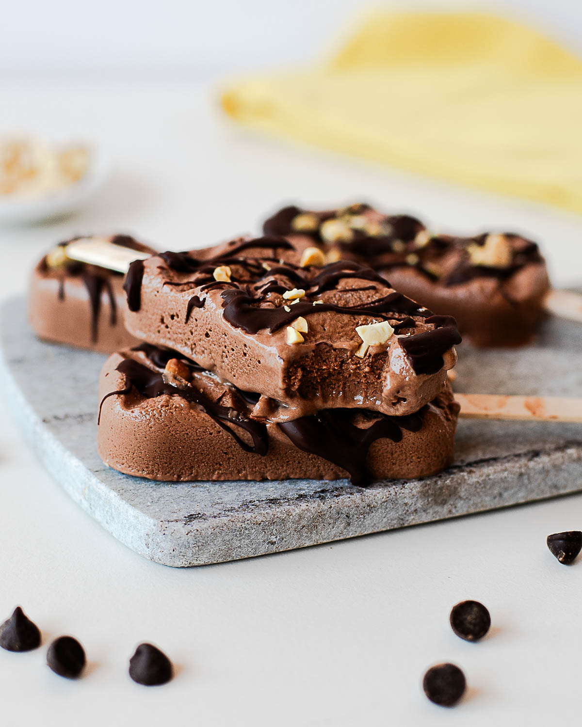 Bitten chocolate protein popsicle stacked on another popsicle, highlighting the smooth, creamy texture and chocolate peanut butter flavor.