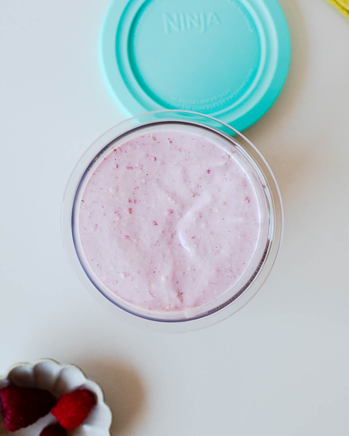 Raspberry protein ice cream base poured into a Ninja Creami pint container before freezing overnight. Made with cottage cheese, raspberries, and vanilla protein powder.