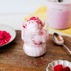 Creamy raspberry protein ice cream scooped into a glass dessert cup and topped with crushed freeze-dried raspberries. An easy high-protein Ninja Creami dessert made with cottage cheese.