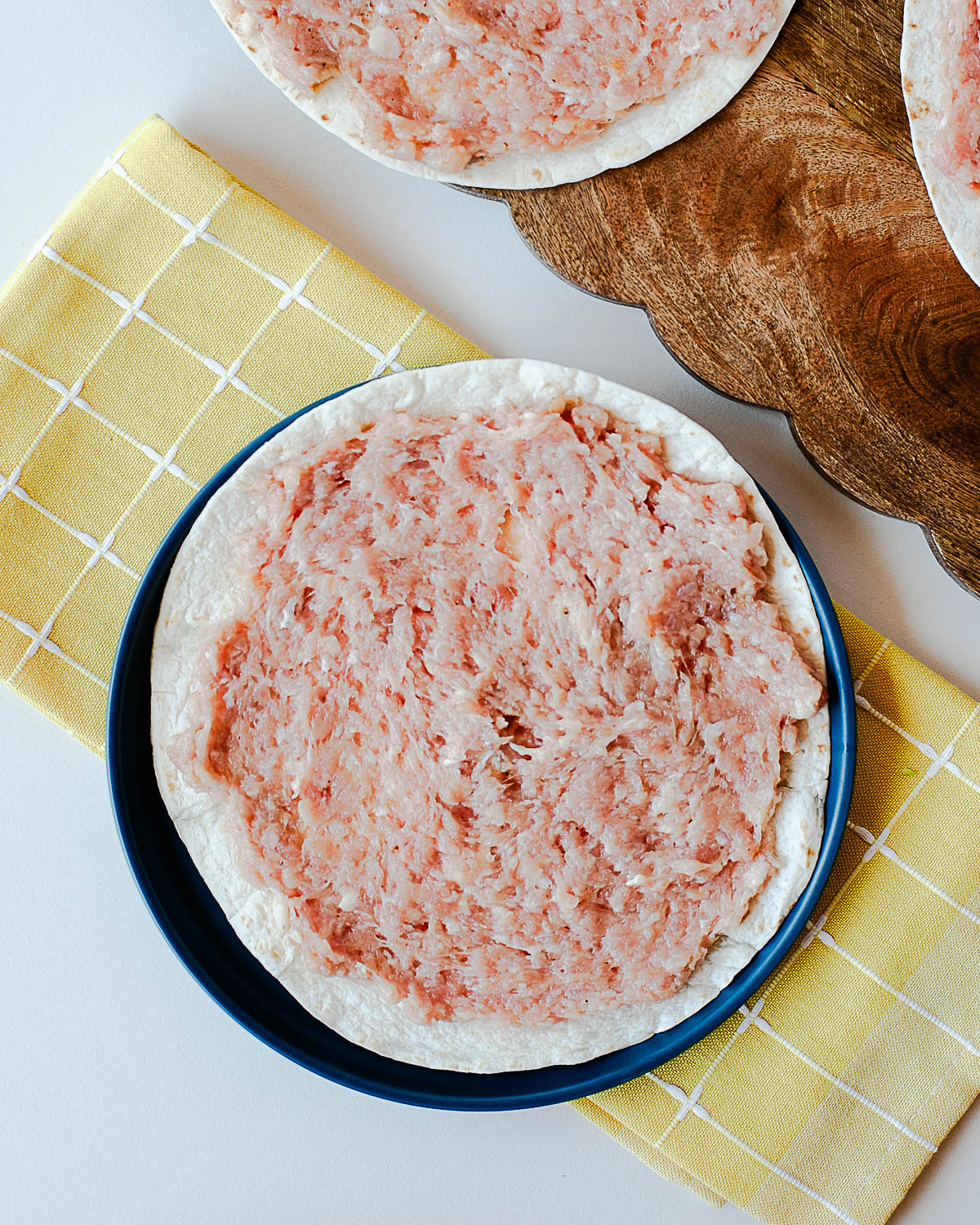 Ground chicken pressed into corn tortillas before cooking for street corn chicken smash tacos.