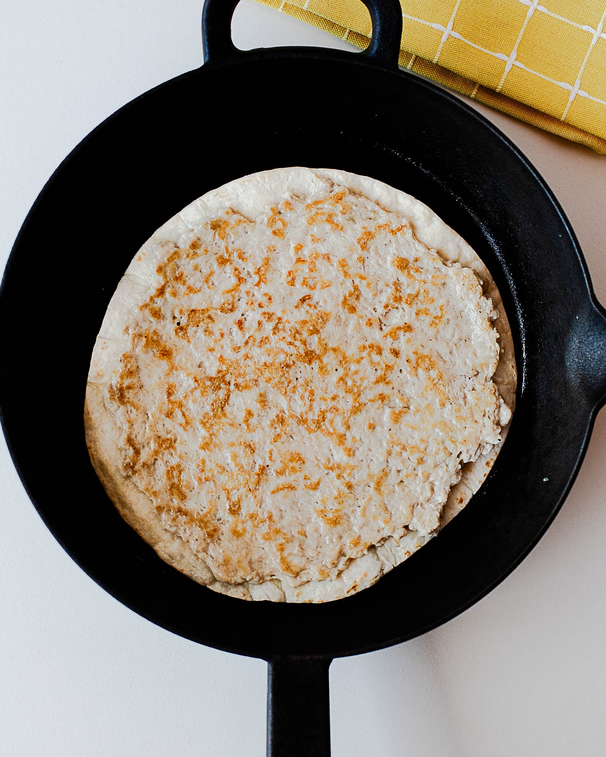 Chicken smash taco cooking in a cast-iron skillet until golden and crispy.